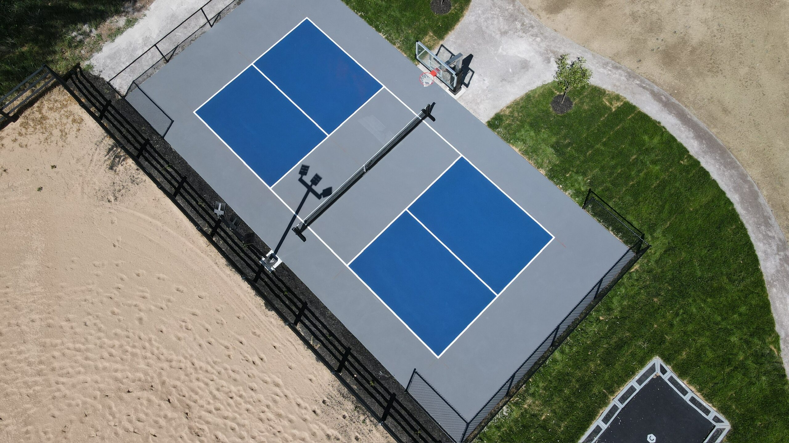 Aerial view of multi-sport complex with pickleball courts, basketball hoop, and gaga pit