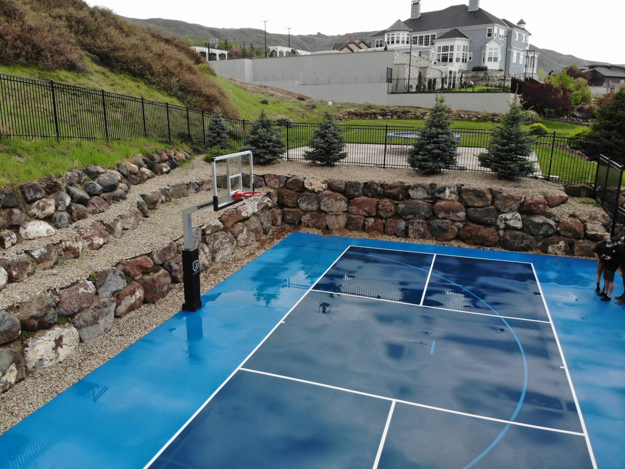 Backyard basketball and pickleball court with landscaped yard
